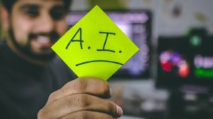Man holding a Post-it with “A.I.” written