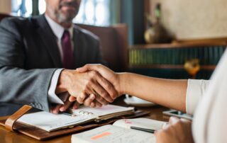 Two people shaking hands over a desk
