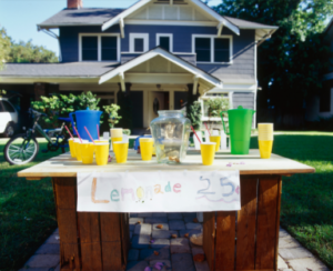 lemonade stand in front of blue house